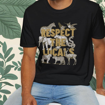 Man wearing a black t-shirt with animal graphics and text, sitting on a white stool with a green leafy background.