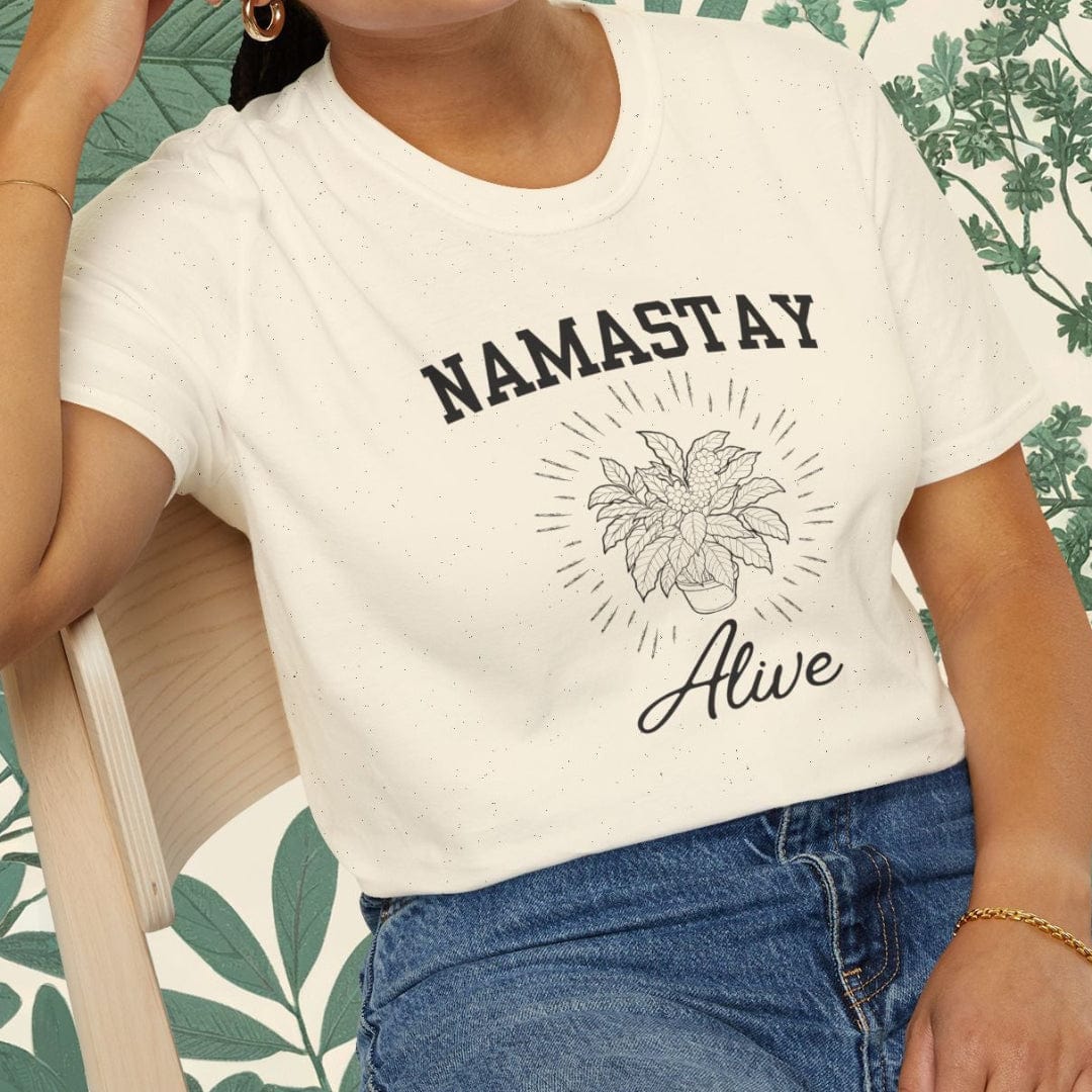 Person wearing a white t-shirt with 'NAMASTAY Alive' text and sitting on a chair.