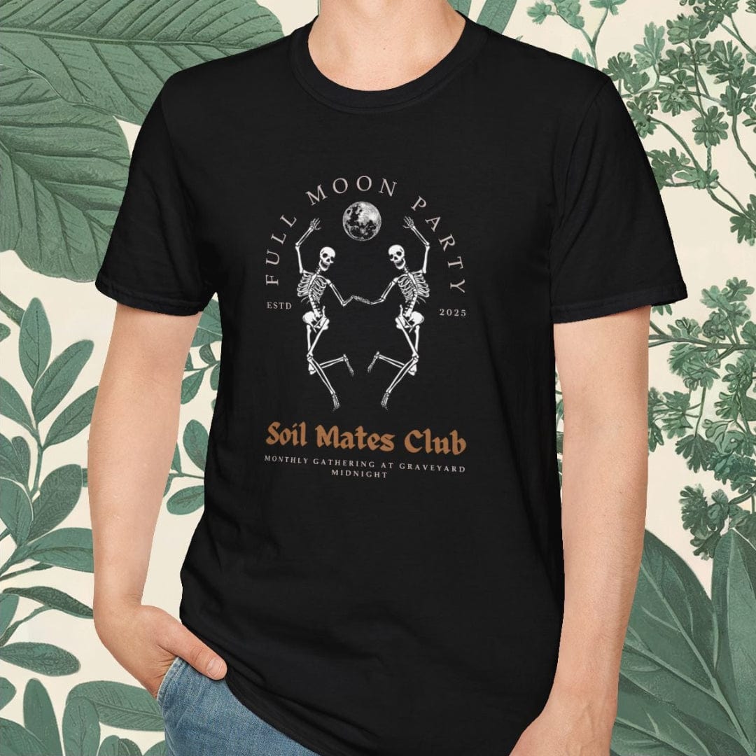 Person wearing a black t-shirt with graphic design and text, standing against a decorative background with green leaves.