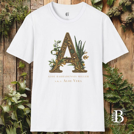 White t-shirt with a decorative letter 'A' design on a wooden background with plants