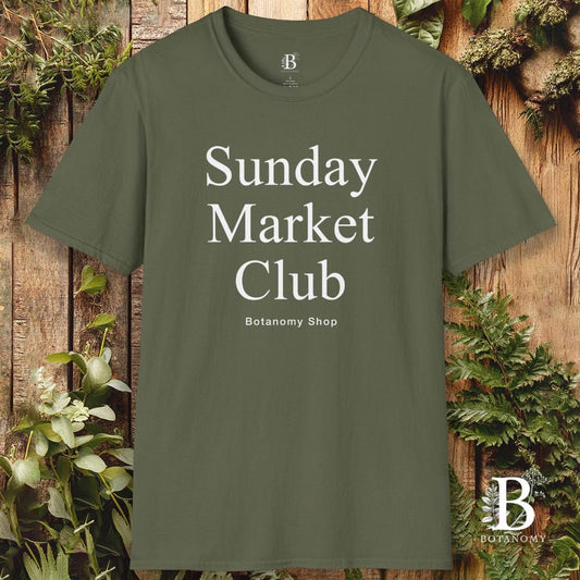 Green t-shirt with 'Sunday Market Club' text on a wooden background with plants