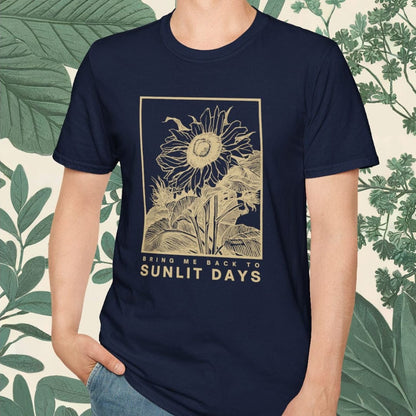 Man wearing a navy blue t-shirt with a sunlit days graphic design against a leafy background