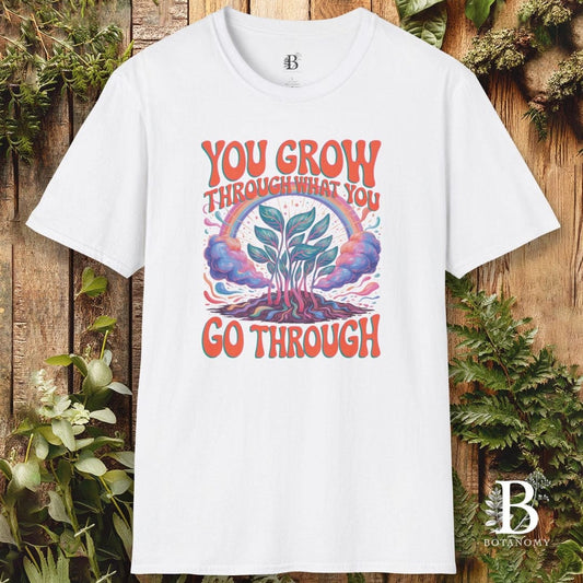 White t-shirt with a graphic design and text on a wooden background with plants