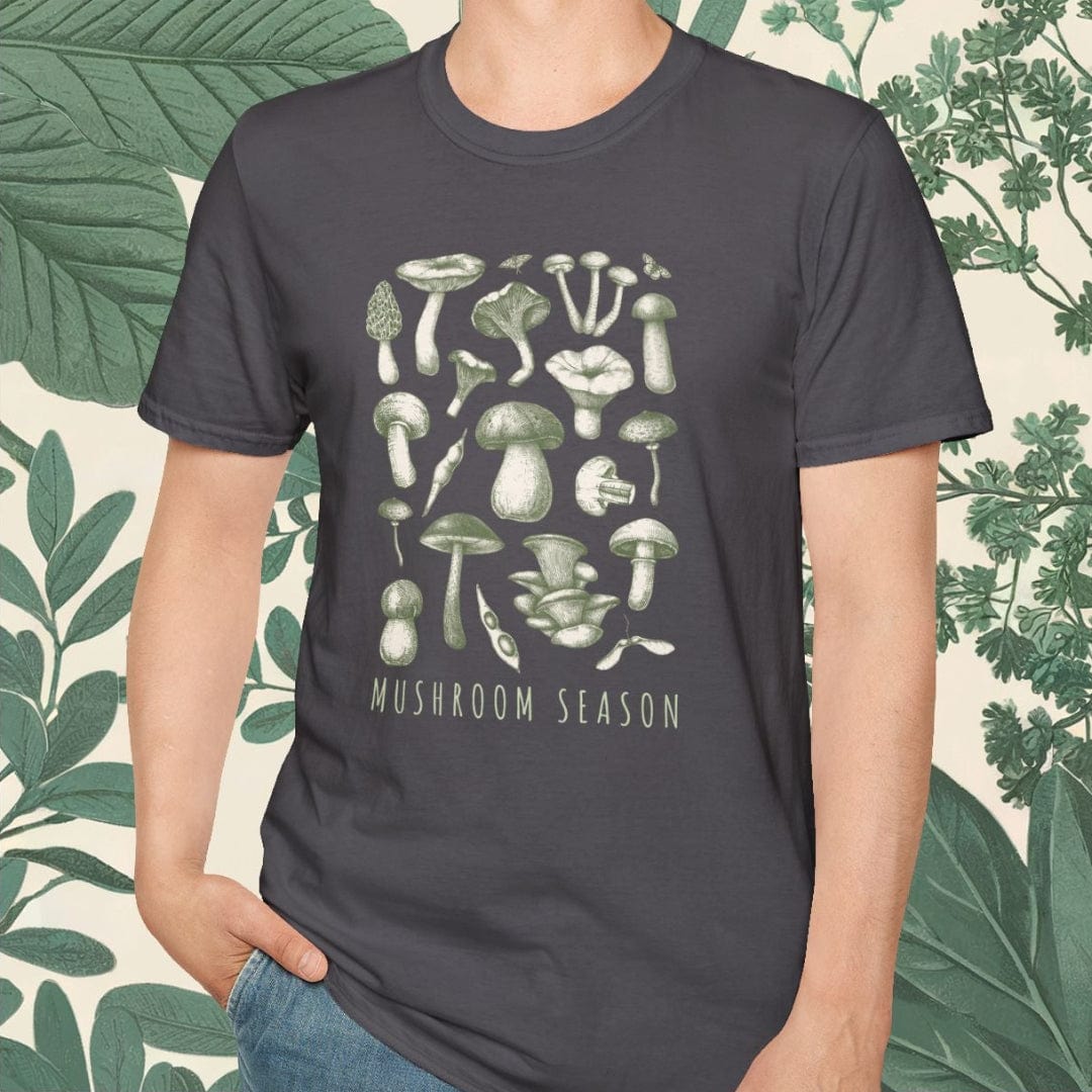 Person wearing a t-shirt with mushroom design and 'Mushroom Season' text, standing against a leafy green background.