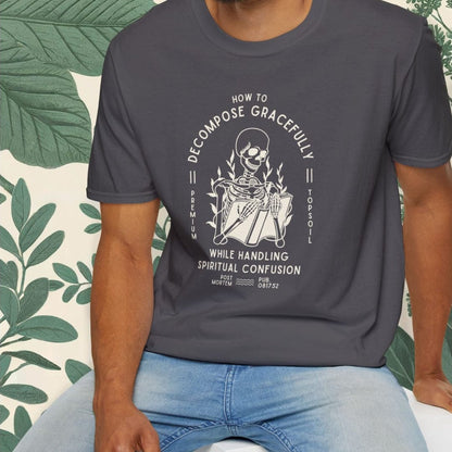 Man wearing a dark gray t-shirt with a graphic design sitting on a white stool against a light background.
