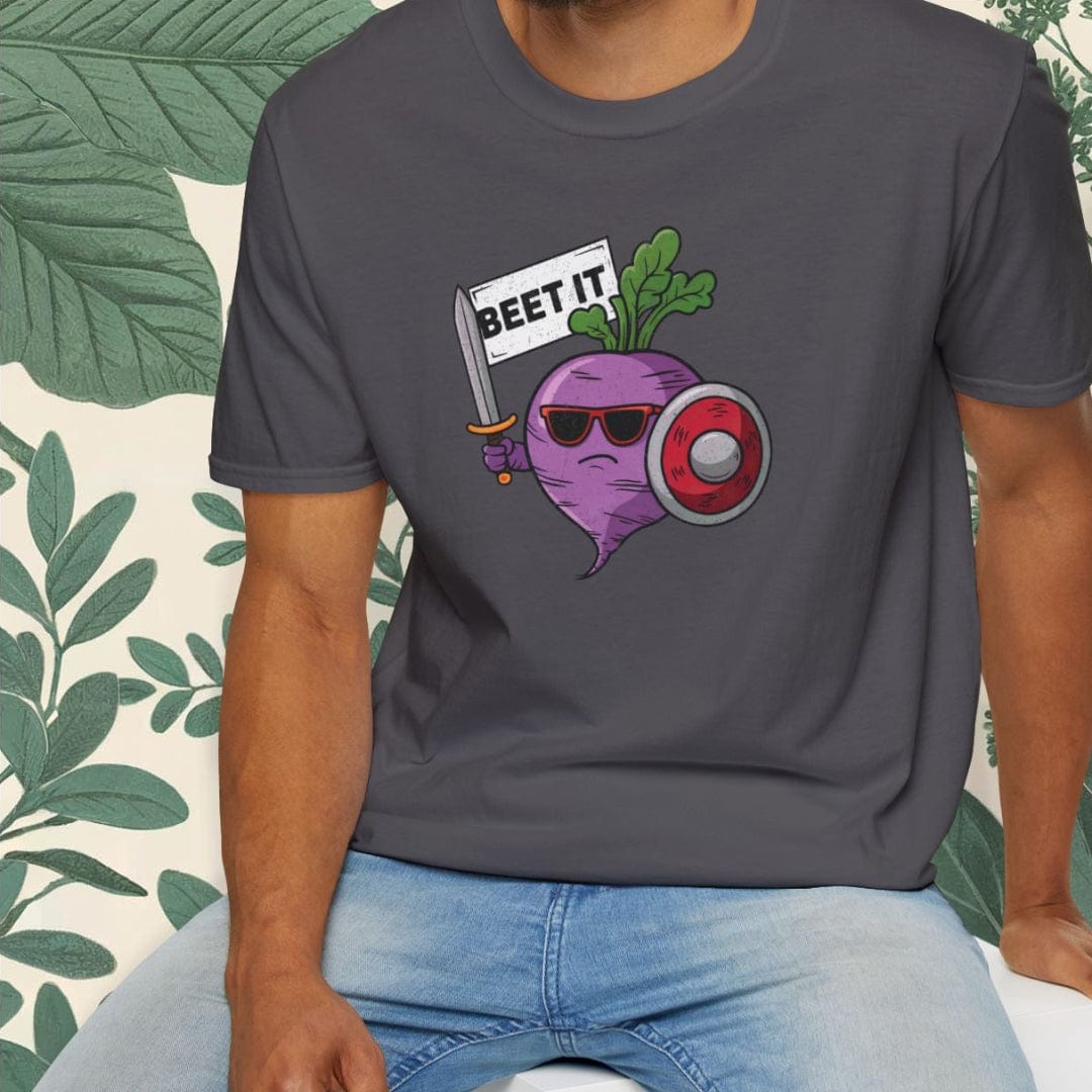 Man wearing a dark gray t-shirt with a graphic design sitting on a white stool against a light-colored wall with green leafy plants.