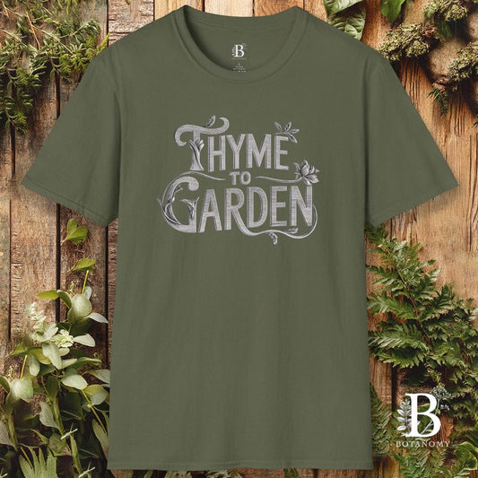 Green t-shirt with 'Thyme to Garden' text on a wooden background with plants