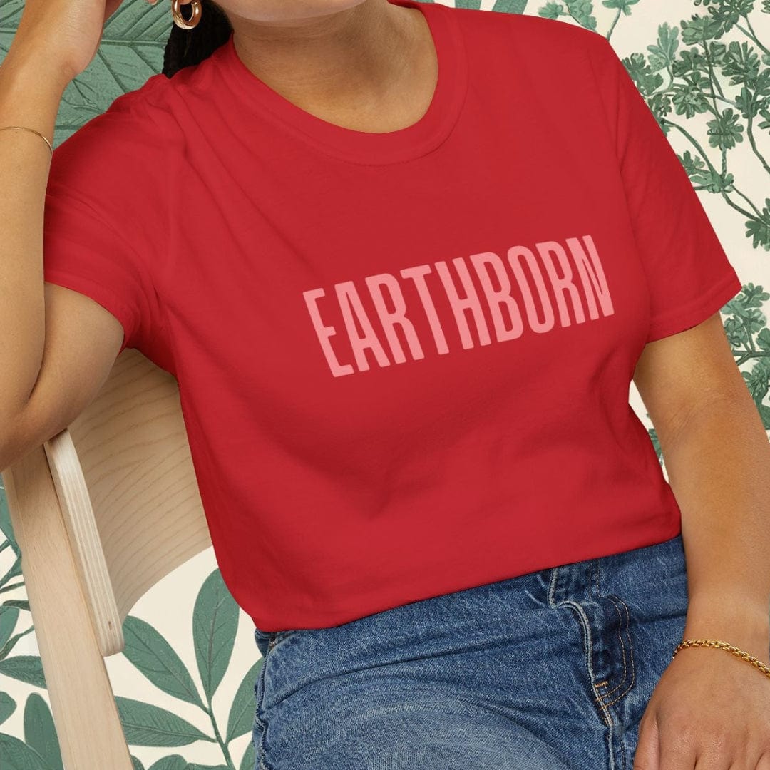 Person wearing a red 'EARTHBORN' t-shirt sitting on a chair with a leafy background