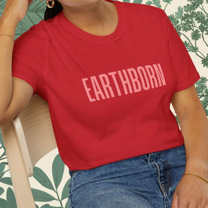 Person wearing a red 'EARTHBORN' t-shirt sitting on a chair with a leafy background