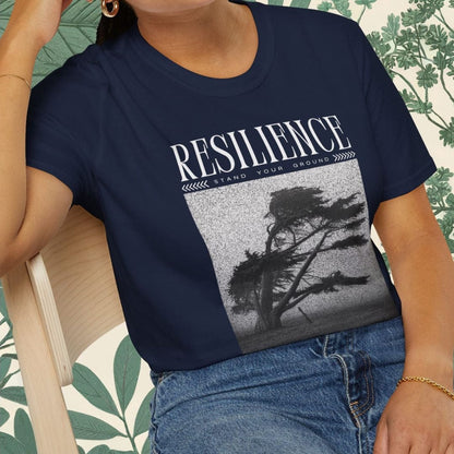 Person wearing a navy blue t-shirt with 'RESILIENCE' graphic design, sitting on a chair.
