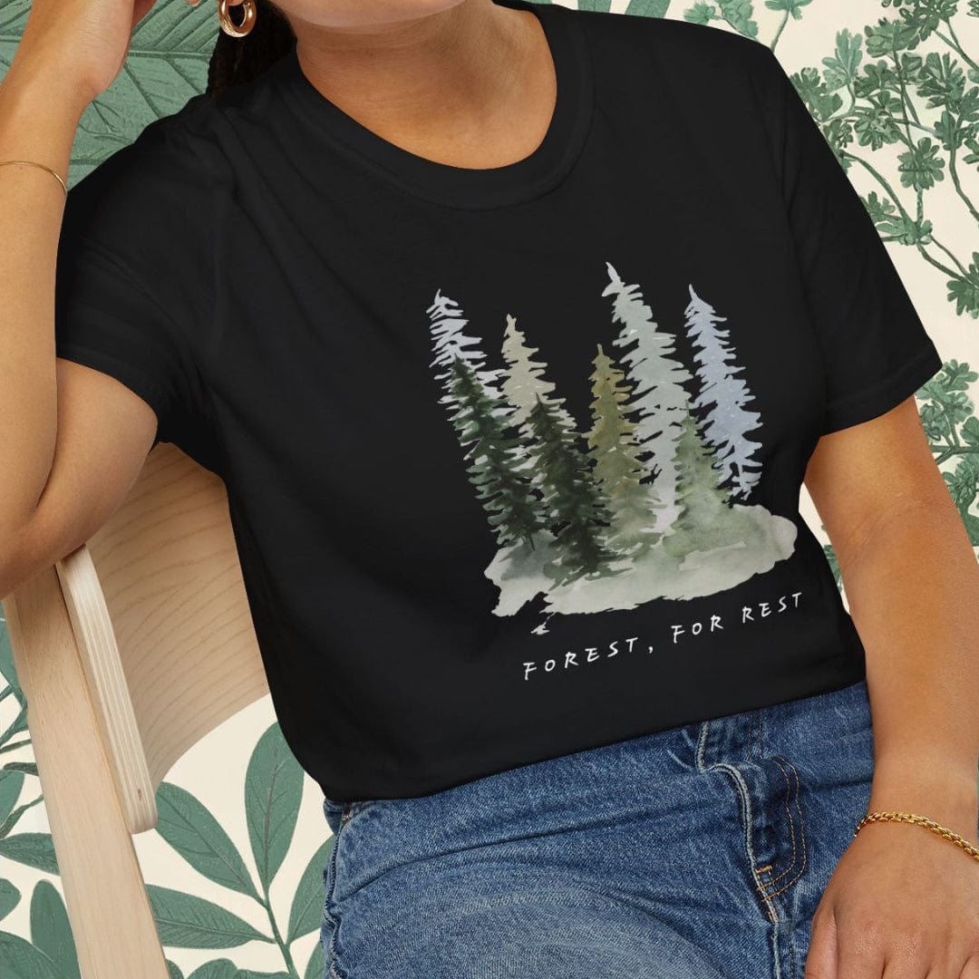 Person wearing a black t-shirt with a forest design and text, sitting on a chair.