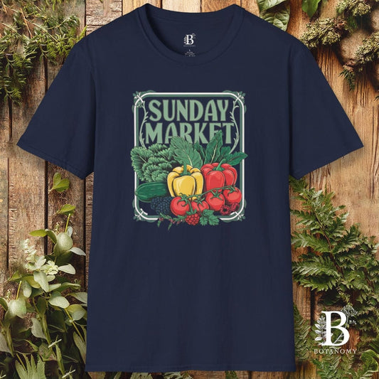 Navy blue t-shirt with 'Sunday Market' graphic design featuring fruits and vegetables on a wooden background.
