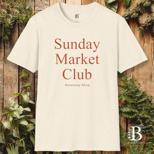 White t-shirt with 'Sunday Market Club' text on a wooden background with plants