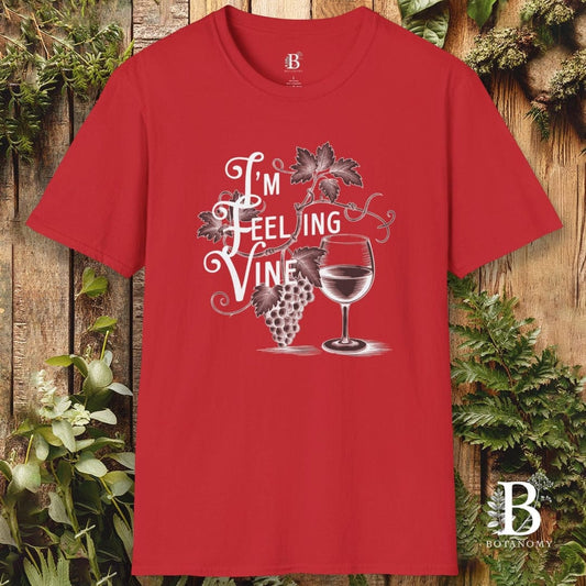 Red t-shirt with 'I'm Feeling Vine' graphic design on a wooden background with greenery.