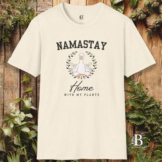 Beige t-shirt with 'Namastay Home with My Plants' design on a wooden background with plants.