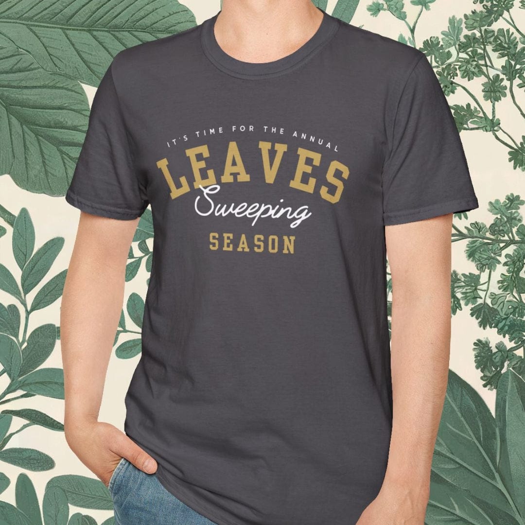 Person wearing a dark gray t-shirt with 'Leaves Sweeping Season' text, standing against a leafy background.