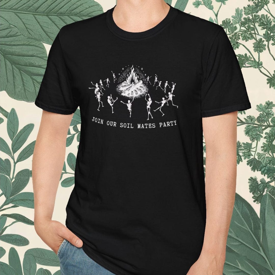 Person wearing a black t-shirt with a graphic design and text, standing against a decorative background with green leaves.