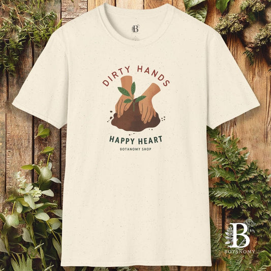 White t-shirt with 'Dirty Hands, Happy Heart' graphic design on a wooden background with plants.