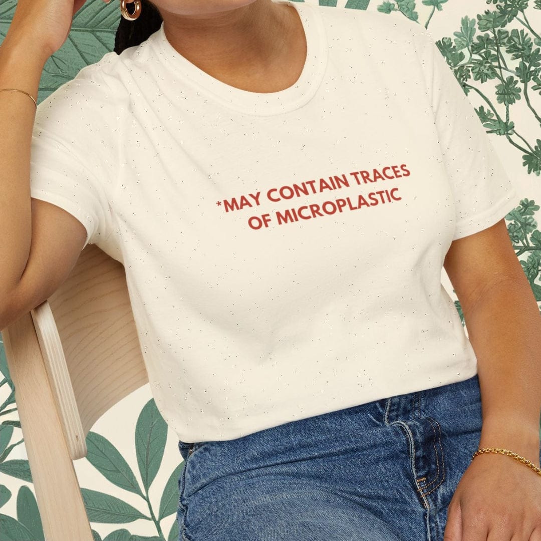 Person wearing a white t-shirt with text, sitting on a chair with a leafy background