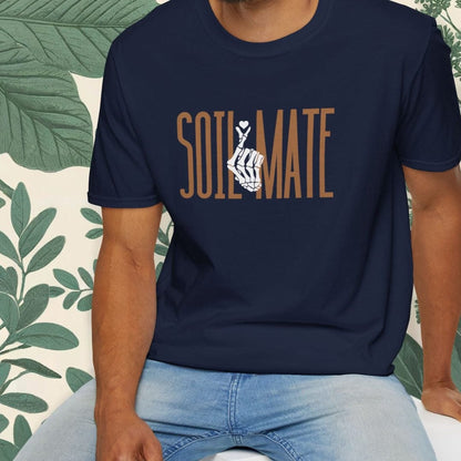 Man wearing a navy blue t-shirt with 'SOULMATE' printed on it, sitting against a white background with green leafy elements.