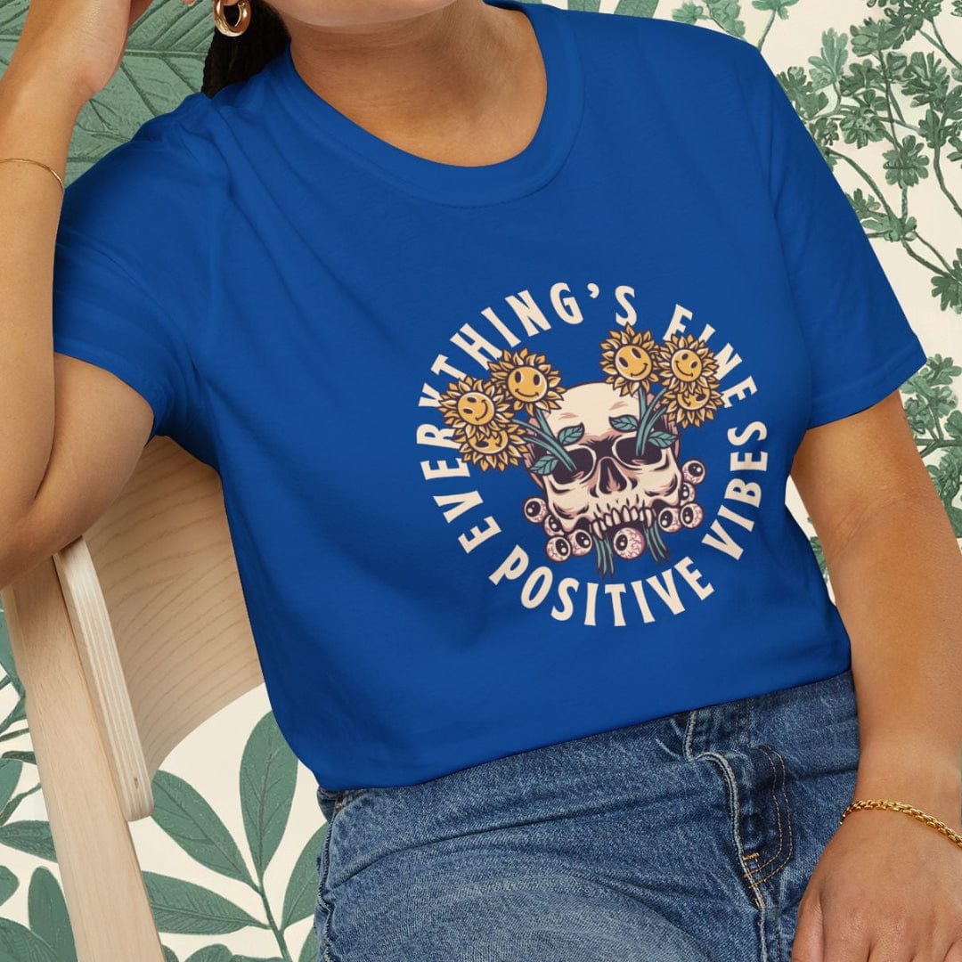 Person wearing a blue t-shirt with a graphic design and text, sitting on a chair.