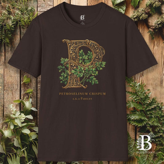 Brown t-shirt with decorative letter 'P' design on a wooden background with plants