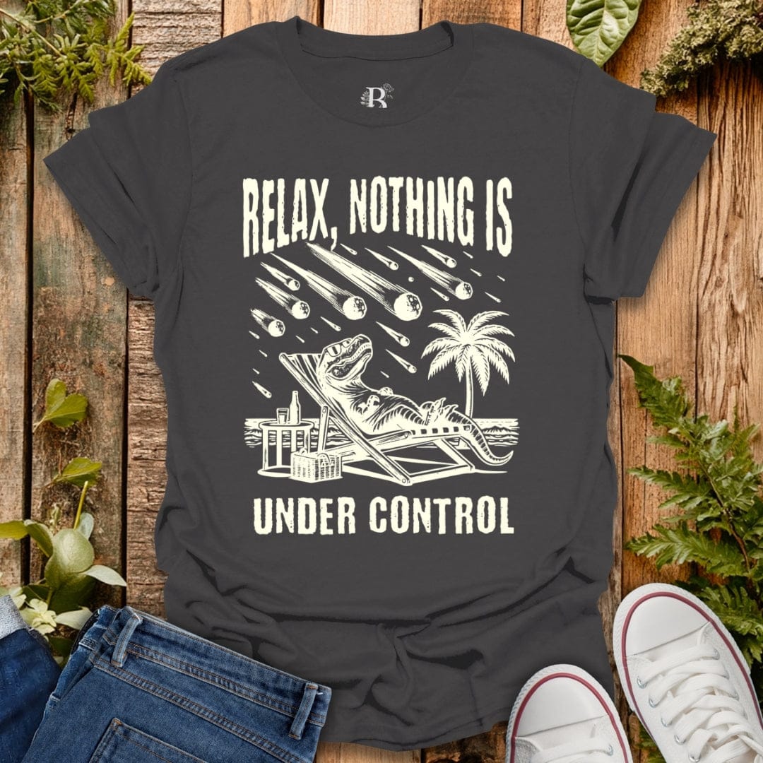 Gray t-shirt with white graphic and text 'Relax, Nothing is Under Control' on a wooden surface with plants.