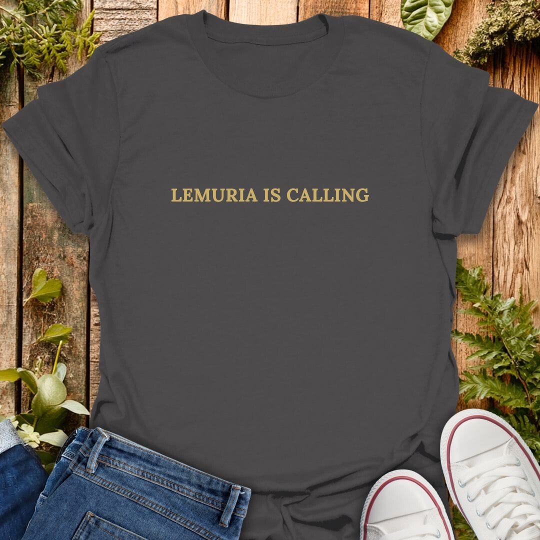 Grey t-shirt with 'Lemuria is calling' text on a wooden surface with plants, jeans and sneakers.