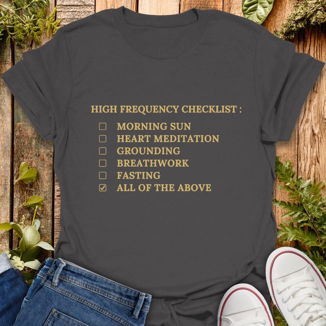 Grey t-shirt with 'High Frequency Checklist' text on a wooden surface with plants, jeans and sneakers.