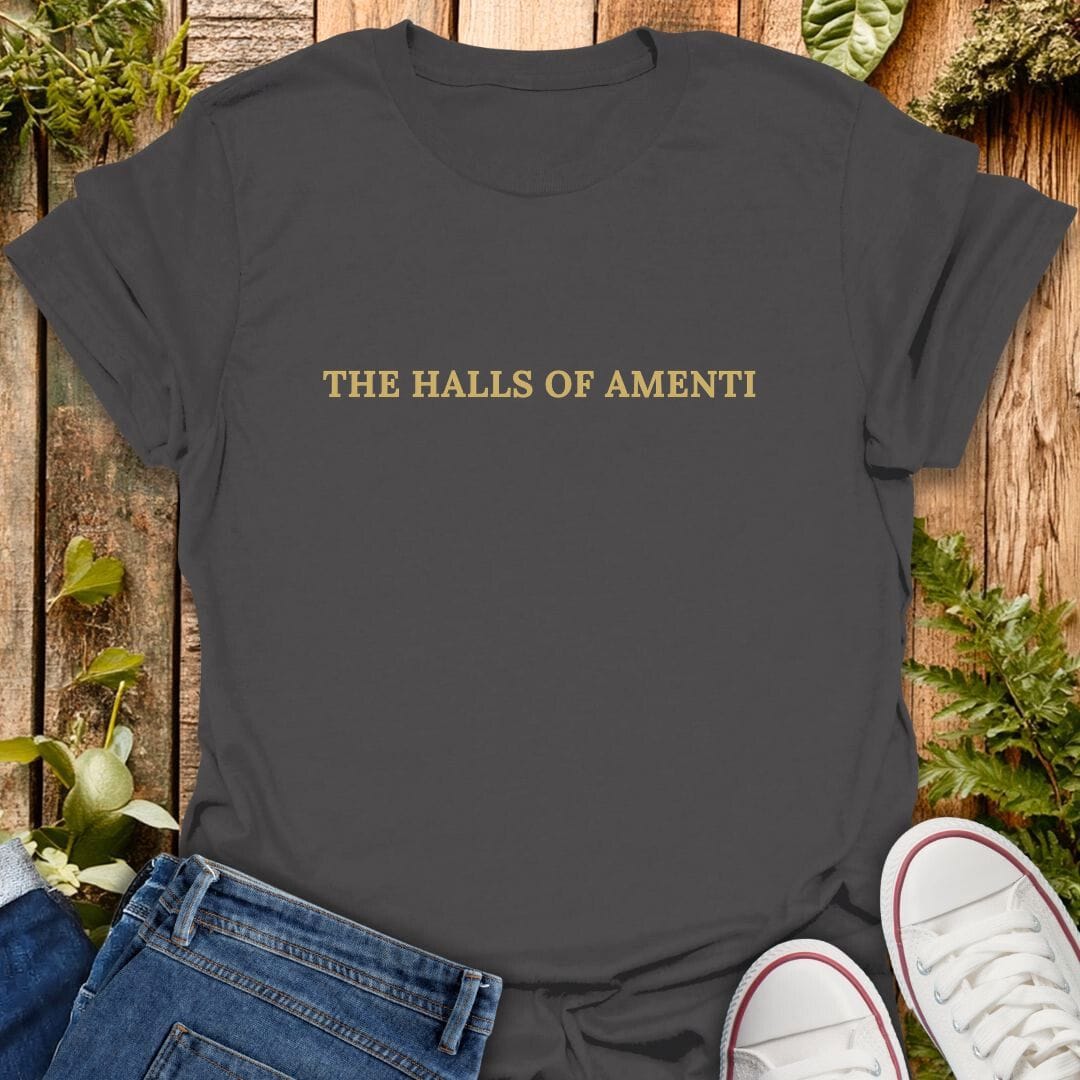 Grey t-shirt with 'The halls of amenti' text on a wooden surface with plants, jeans and sneakers.