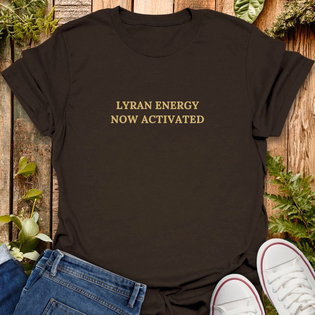 Brown t-shirt with text "Lyran Energy Now Activated" on wooden background and jeans and sneakers.
