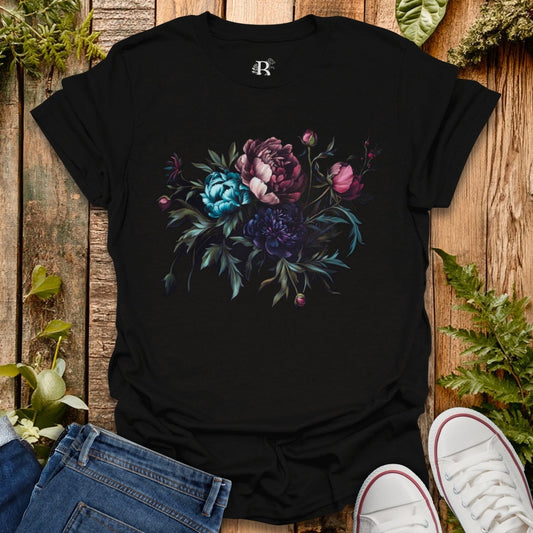 Black t-shirt with floral design on a wooden surface with jeans and sneakers.