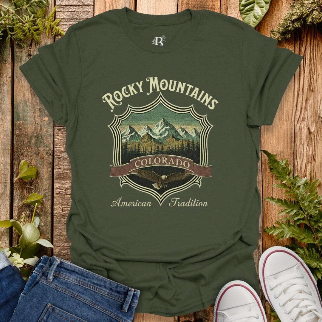 Green t-shirt with 'Rocky Mountains Colorado American Tradition' design on a wooden background.
