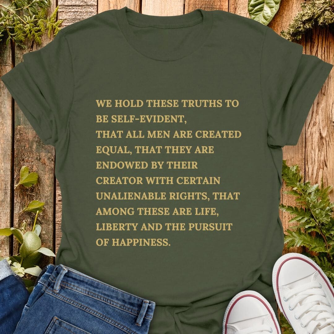 Green t-shirt with declaration of independence text on a wooden background with plants, jeans and sneakers.