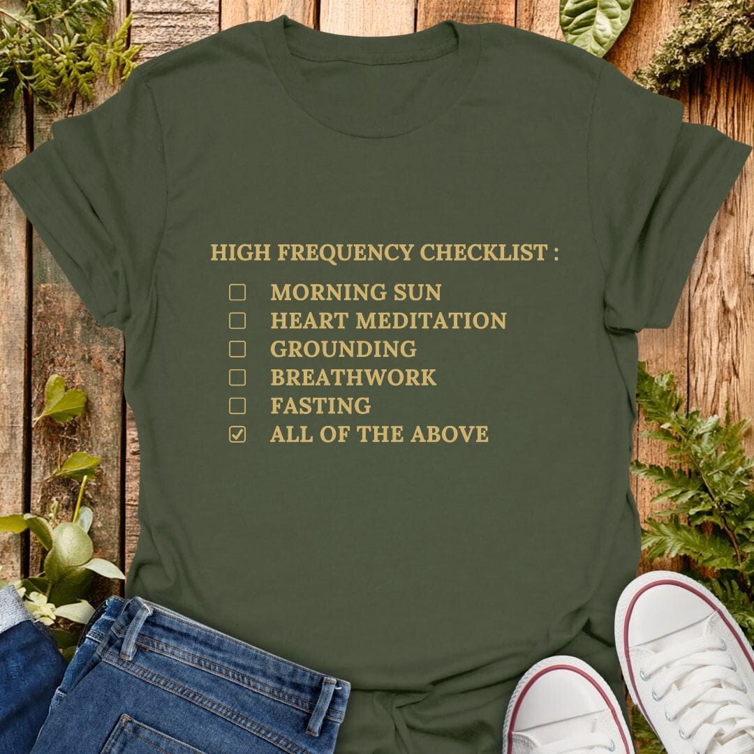 Green t-shirt with 'High Frequency Checklist' text on a wooden surface with plants, jeans and sneakers.