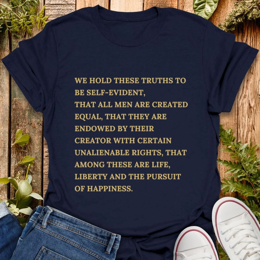 Navy blue t-shirt with declaration of independence text on a wooden background with plants, jeans and sneakers.