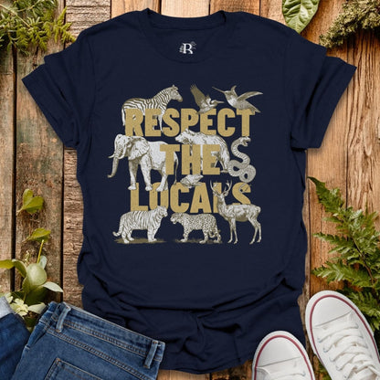 Navy blue t-shirt with animal graphics and 'Respect the Locals' text on a wooden surface.