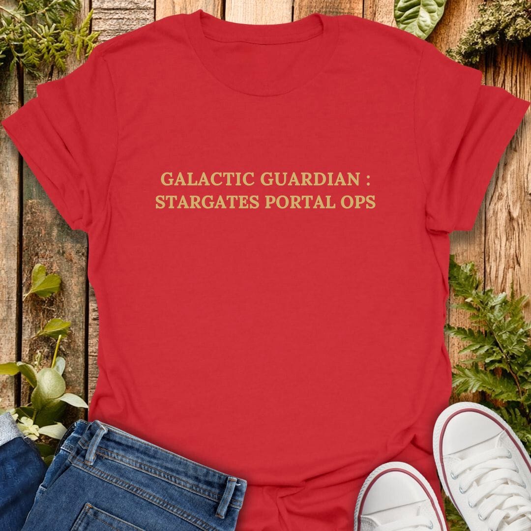 Red t-shirt with text 'Galactic Guardian: Stargates Portal Ops' on a wooden background with plants, jeans and sneakers.