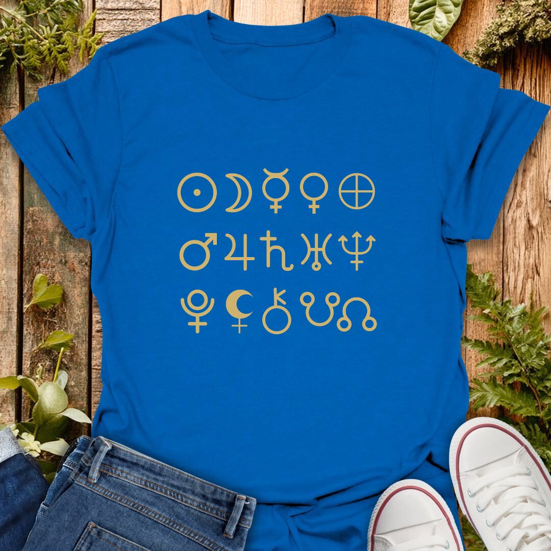 Blue t-shirt with gold planetary symbol design on a wooden surface with plants.