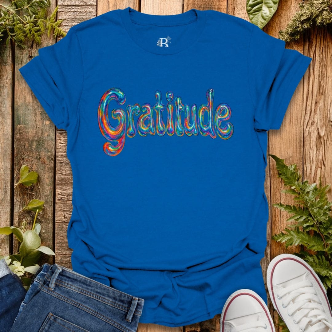 Blue t-shirt with 'Gratitude' in colorful letters on a wooden background