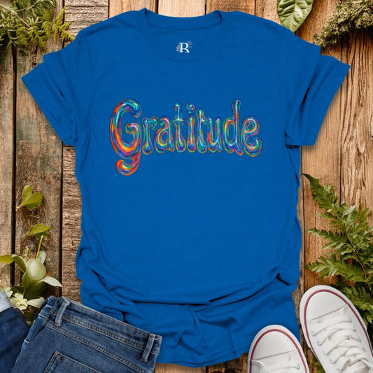 Blue t-shirt with 'Gratitude' in colorful letters on a wooden background