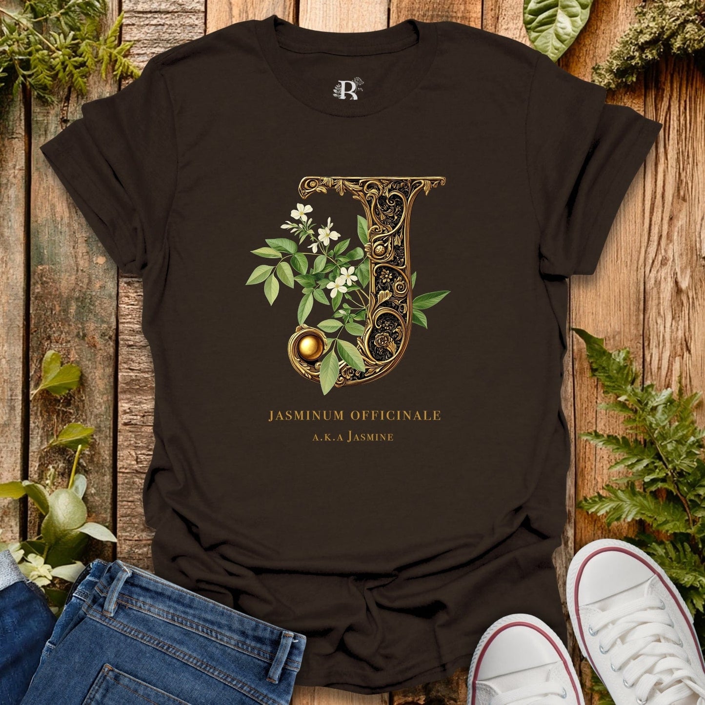 Black t-shirt with decorative letter 'J' design on a wooden surface with plants.