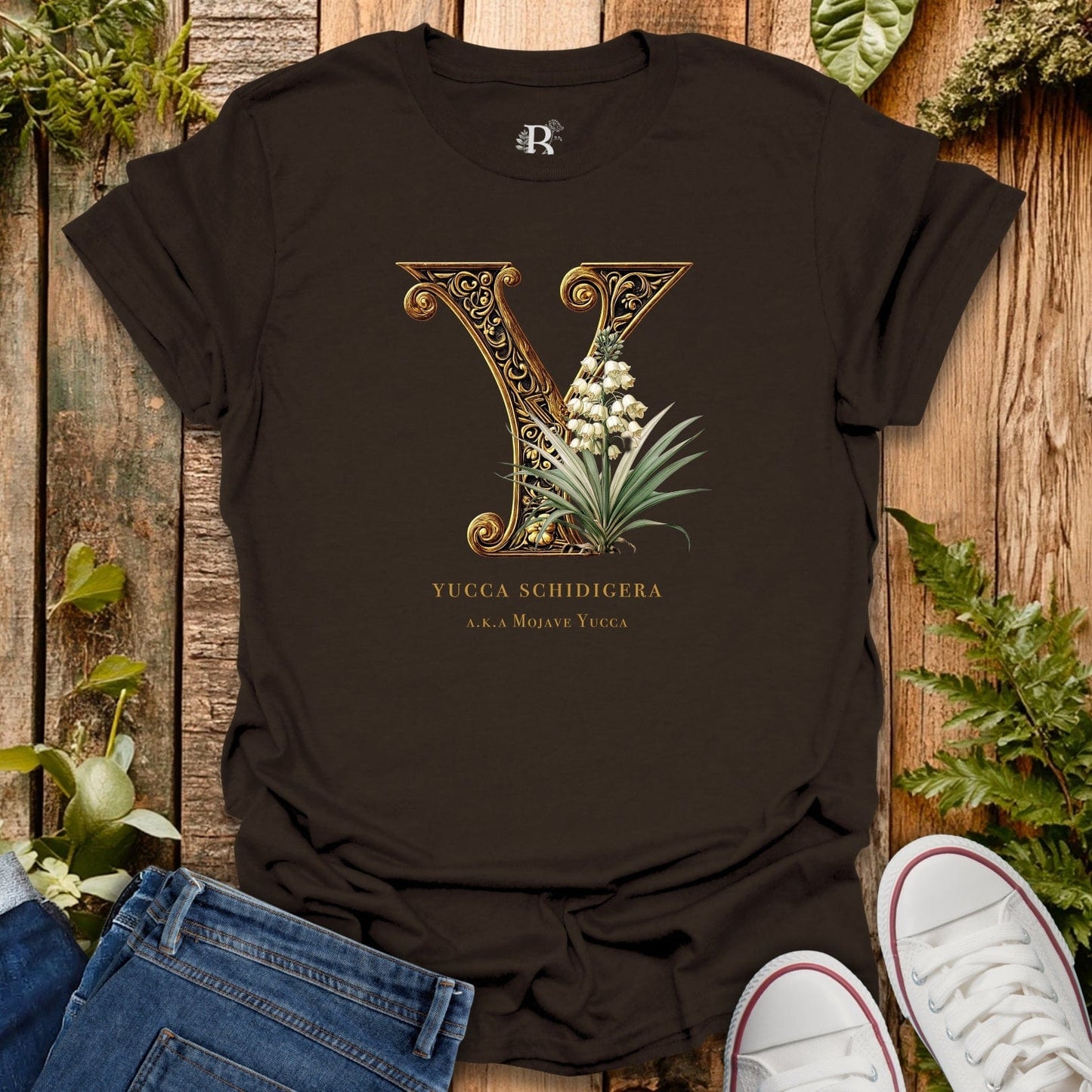 Black t-shirt with decorative letter 'Y' design on a wooden surface with plants.