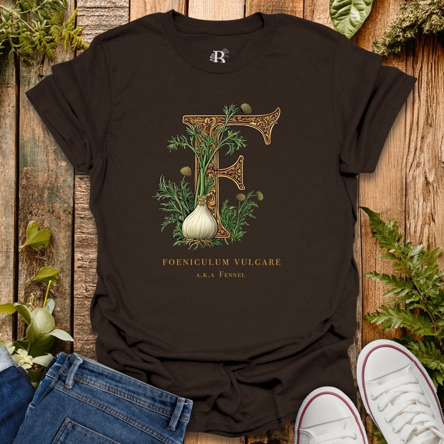 Black t-shirt with botanical design and text on a wooden surface with plants.