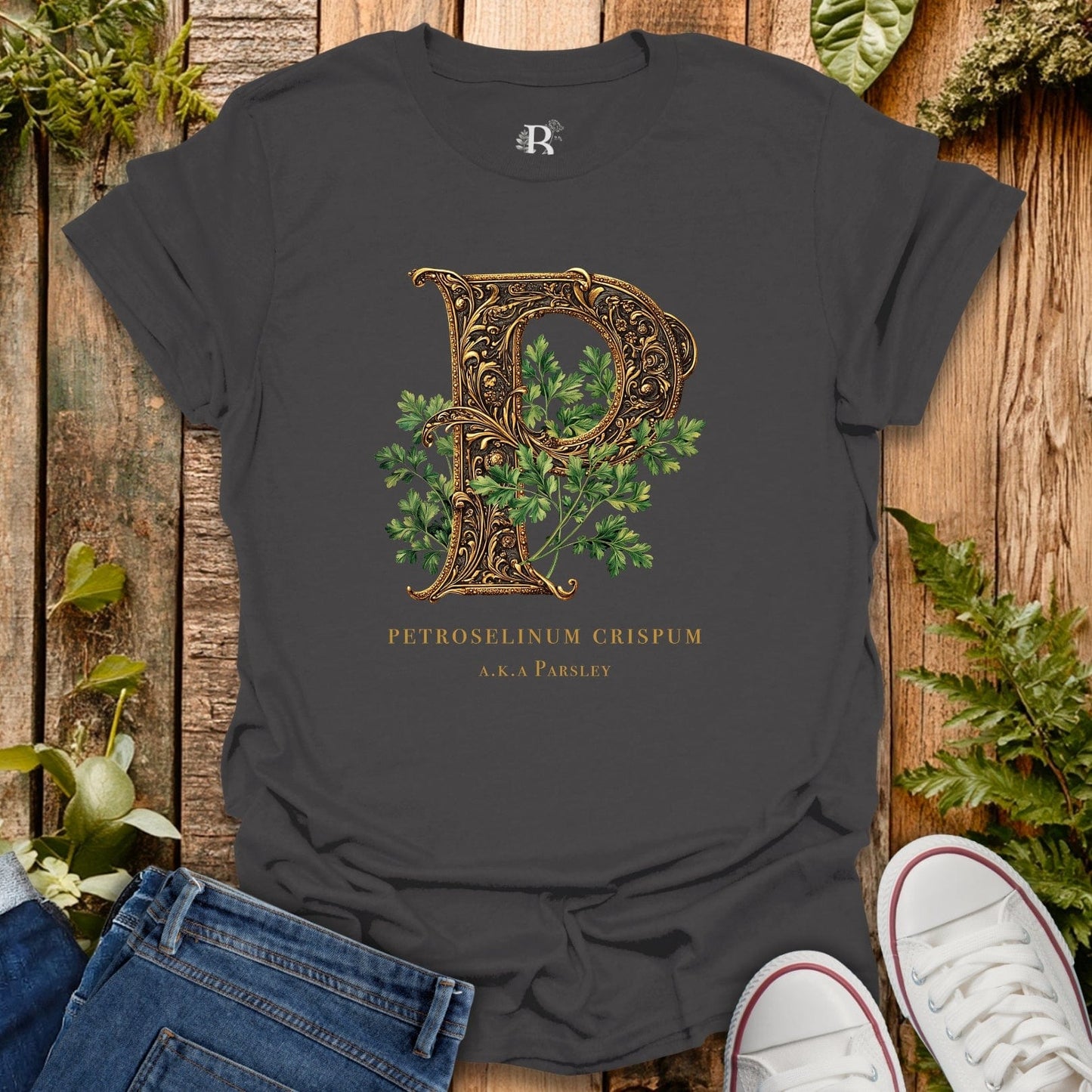Dark gray t-shirt with decorative letter 'P' design on a wooden surface with plants.
