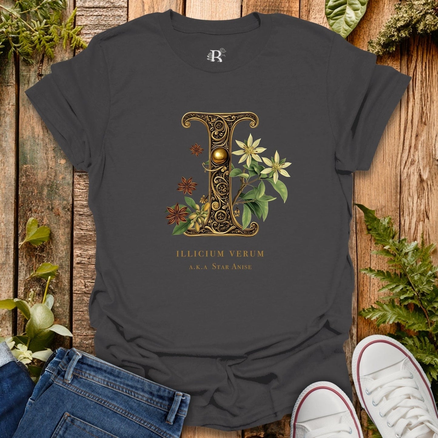 Dark gray t-shirt with decorative letter 'L' design on a wooden surface with plants.