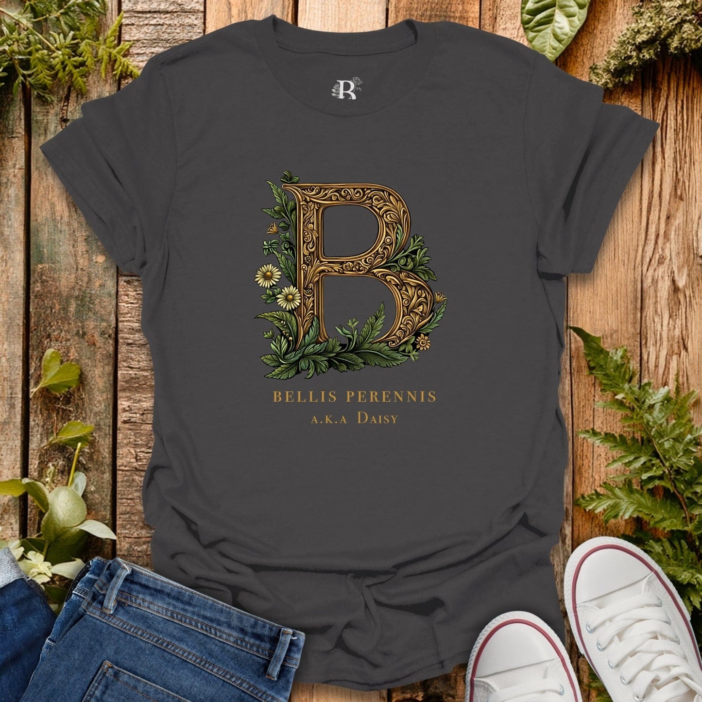 Dark gray t-shirt with decorative letter 'B' design on a wooden surface with plants.