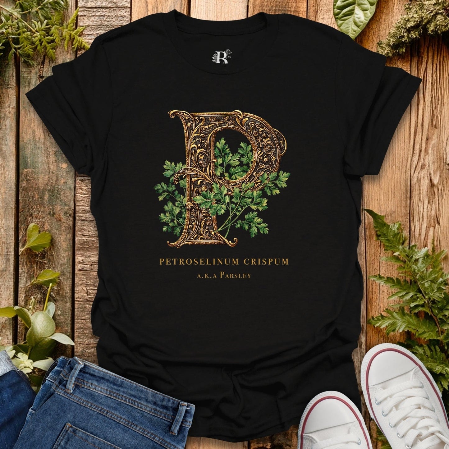 Black t-shirt with decorative letter 'P' design on a wooden surface with plants.
