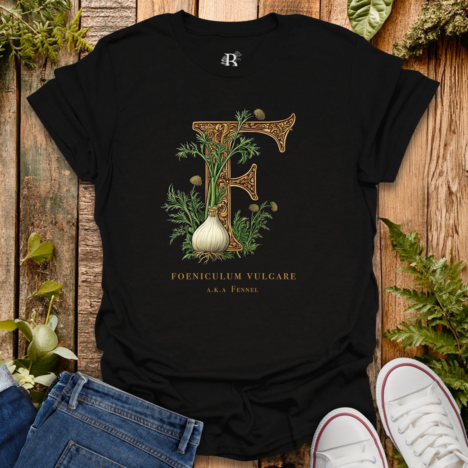 Black t-shirt with botanical design and text on a wooden surface with plants.
