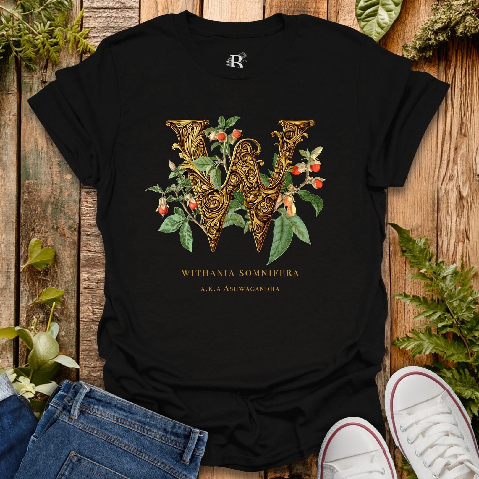 Black t-shirt with decorative letter 'W' design on a wooden surface with plants.